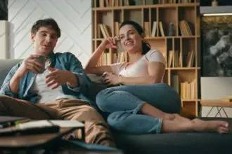 Smiling pair talking couch holding cups coffee. Couple relaxing family evening