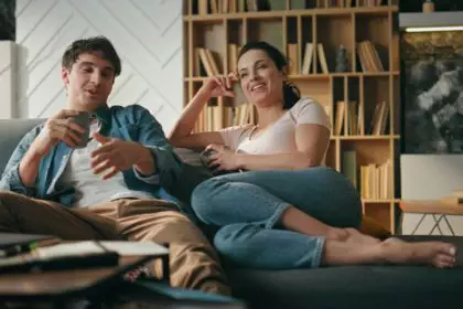 Smiling pair talking couch holding cups coffee. Couple relaxing family evening