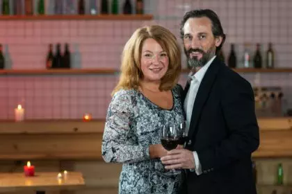 Waist up portrait of excited adult loving couple celebrating special occasion with red wine