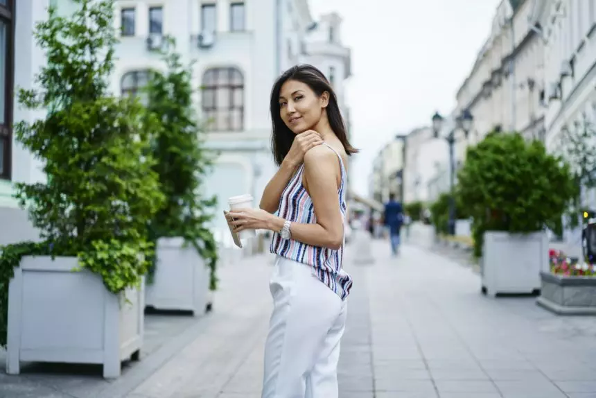 Beautiful Asian tourist posing in city during coffee break