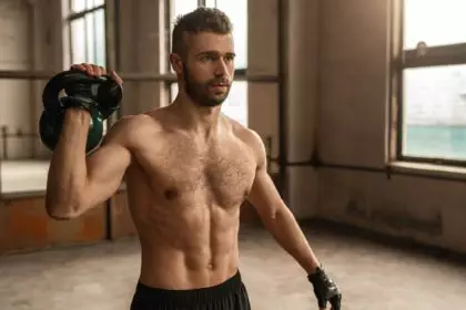 Muscular man training with kettlebell in gym