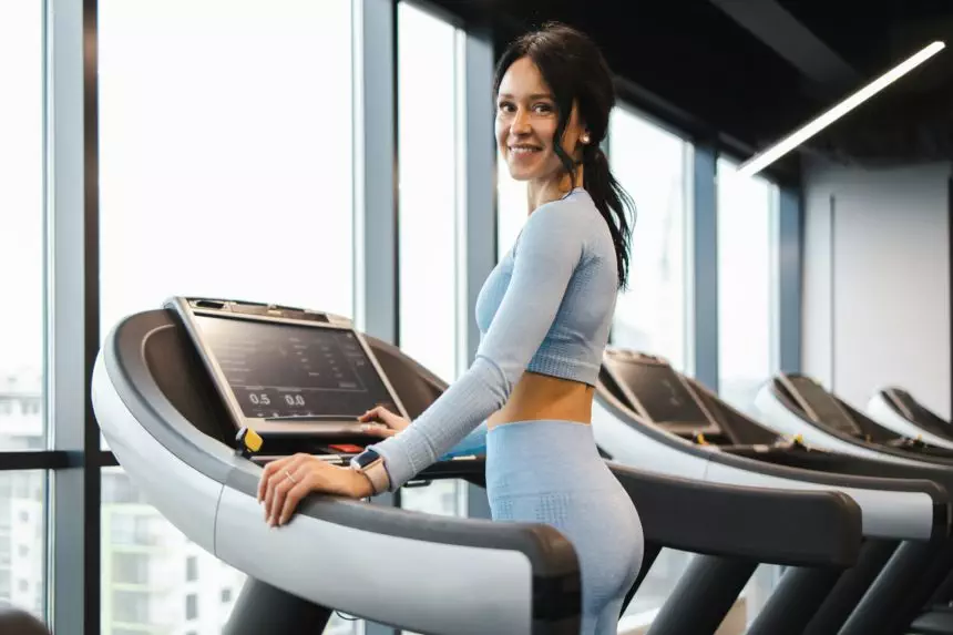 Beautiful fitness brunette woman stands on a treadmill