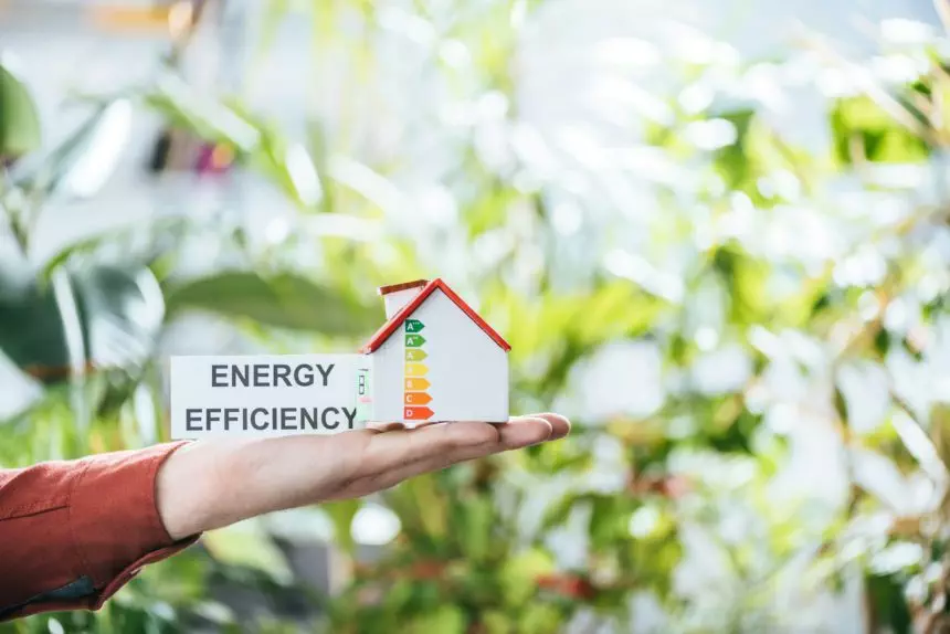 cropped view of man holding card with lettering and carton house in hands, energy efficiency at home