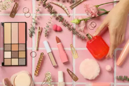 Makeup tools and flowers on a pink background