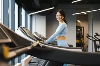 Cheerful fitness girl walking on a treadmill