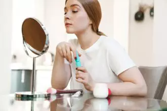Concentrated girl indoors at home with mirror apply makeup