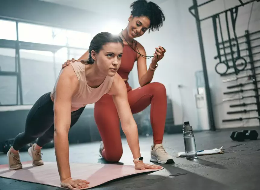 Personal trainer, fitness and stopwatch with a black woman coaching a client in a gym during her wo