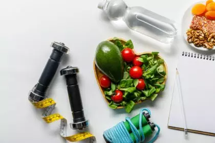 top view of sport equipment with fresh diet food and water on white background