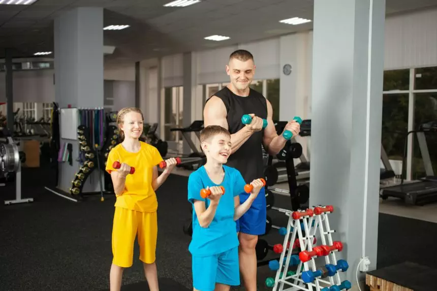 Happy children perform physical exercises in gym with a coach