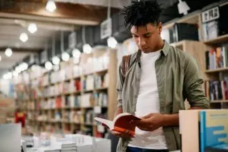 Young black student reading a book in a library,