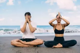 Athletic friends breathing and feeling harmony mindfulness in asana near ocean