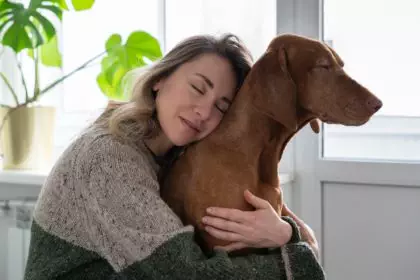 Middle age woman embracing her beloved Wirehaired Vizsla dog at home. Animal therapy concept