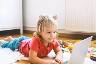 Little girl using computer online technology at home