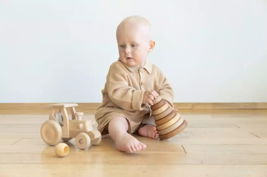 Toddler playing with wooden toys, car, wooden stacking pyramid. Educational game